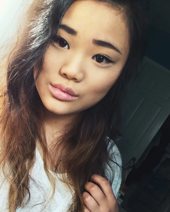 Jeune femme asiatique en chemisier blanc, regardant l'appareil photo, cheveux bruns foncés