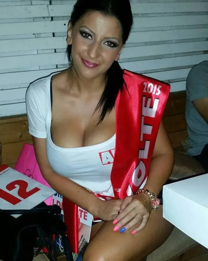 Jeune femme latino en tenue blanche, assise, portant une écharpe rouge avec l'inscription 2015