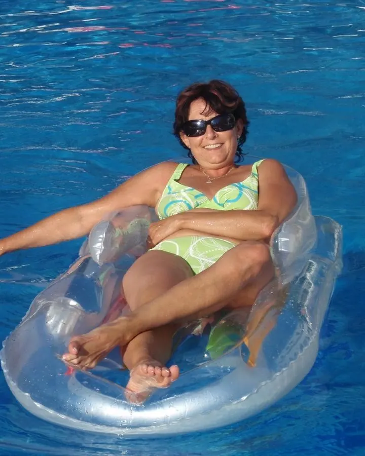Femme en maillot de bain vert, flottant sur un anneau gonflable dans une piscine bleue