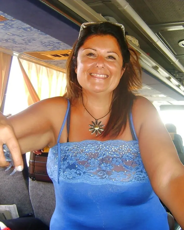 Femme latine en haut bleu dentelle, souriante, assise dans un bus.