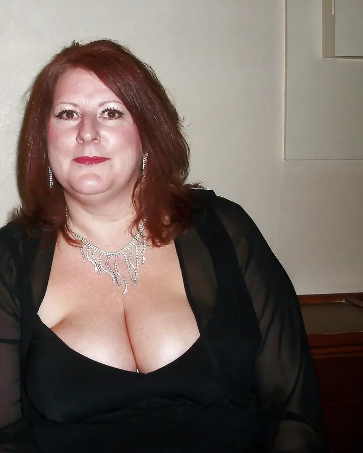Femme aux cheveux châtains, en robe noire transparente, collier argenté, regardant l'appareil.