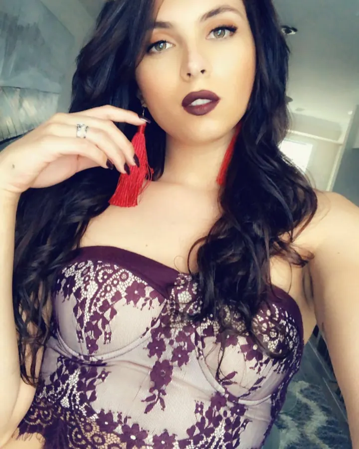 Femme aux cheveux foncés en bustier violet, posant en intérieur.