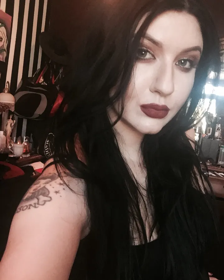 Femme aux cheveux foncés, maquillage sombre, tatouage visible sur l'épaule