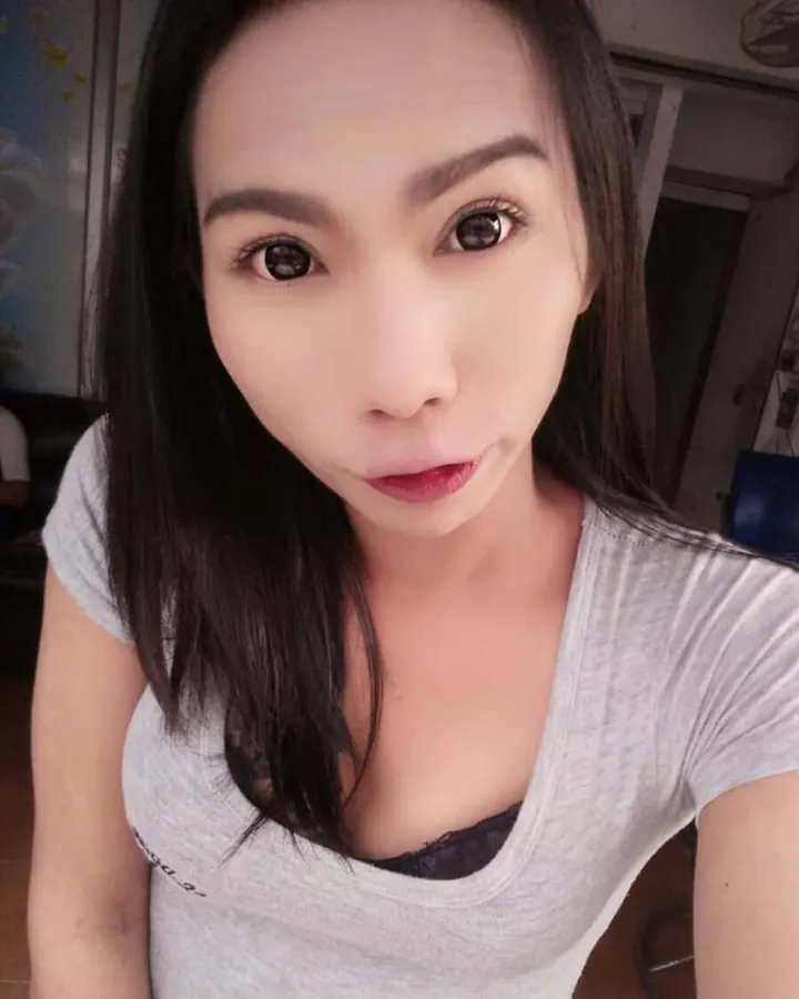 Femme aux cheveux bruns, en robe fleurie, prenant un selfie devant un miroir.