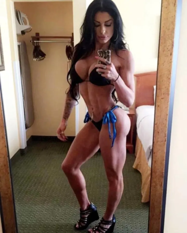 Femme aux cheveux noirs longs, en bikini noir, prenant un selfie dans une chambre d'hôtel.