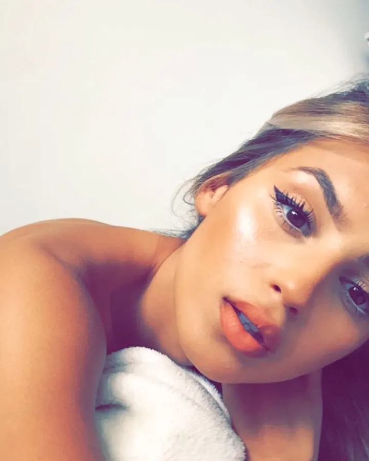 Femme aux cheveux blonds, en gros plan, regardant vers le côté, enveloppée dans une serviette blanche.