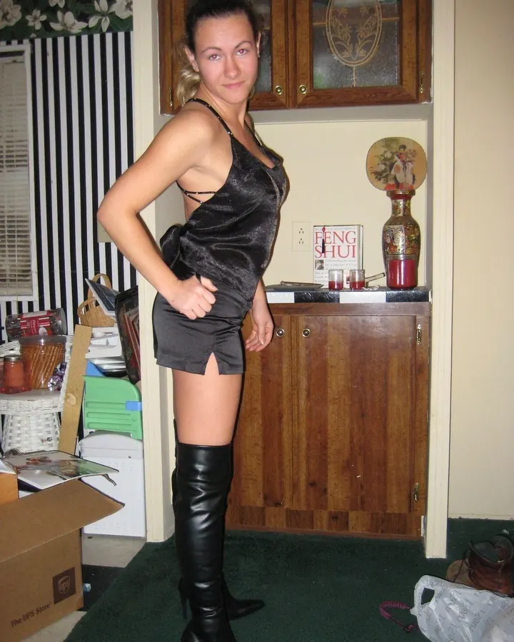 Femme aux cheveux noirs, portant une robe noire transparente, assise sur une structure métallique, les jambes croisées, pieds nus.