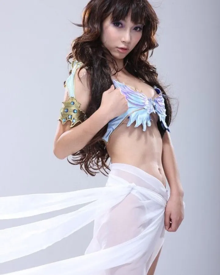 Jeune femme asiatique en tenue blanche et transparente, posant devant un fond gris